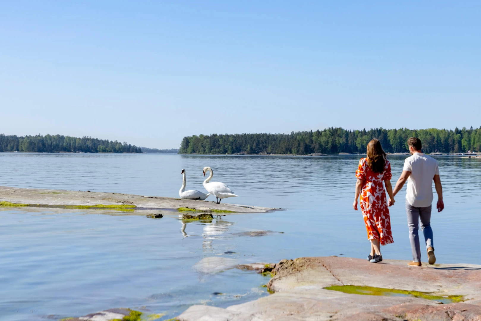 Mies ja nainen käsi kädessä meren rannalla