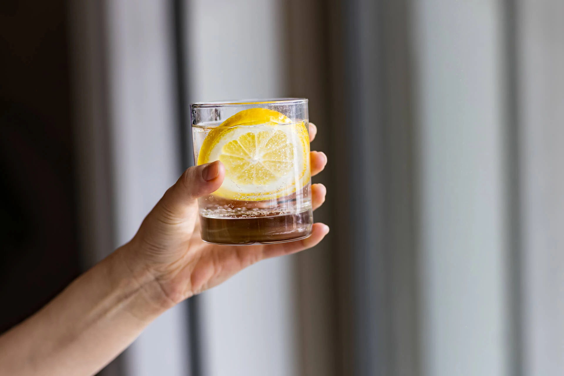 Nainen pitää vesilasia kädessä pitääkseen nestetasapainosta huolta.