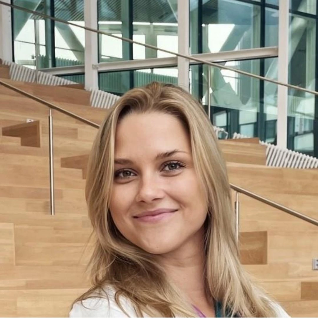 Vaaleahiuksinen nainen hymyilee kameralle taustallaan puiset portaat.